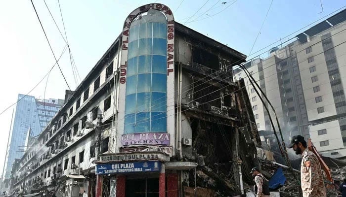 Sindh Rangers personnel walk past charred remains of Gul Plaza shopping centre in Karachi on January 22, 2026. — AFP