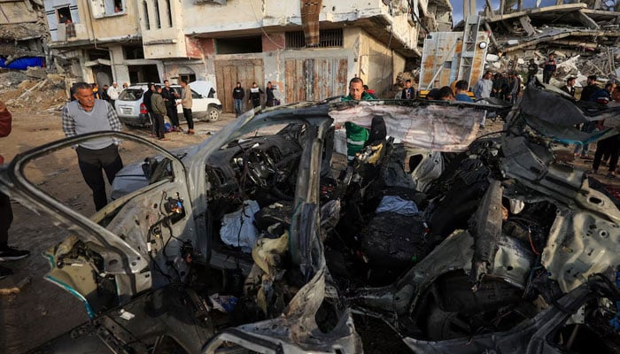 Palestinians inspect the site of an Israeli strike on a car in Gaza City, December 13, 2025. — Reuters