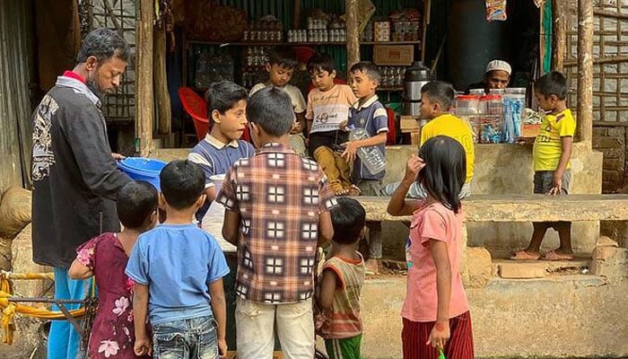 Rohingya refugee children surround a street vendor at the Kutupalong refugee camp in Ukhia, Bangladesh. —AFP