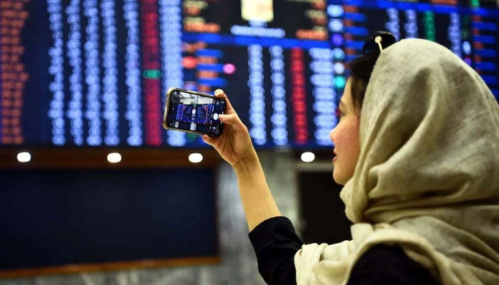 A girl is seen taking picture of electronic screen with her mobile phone at the Pakistan Stock Exchange in Karachi on Wednesday, December 21, 2022. —PPI
