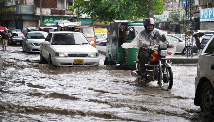 Commuters passing through stagnant rain water accumulated at Khyber Bazar Pull area in Peshawar on April 7, 2026. — APP