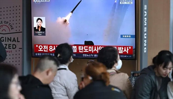 People watch a television screen showing a news broadcast with file footage of a North Korean missile test, at a train station in Seoul on April 8, 2026. —AFP