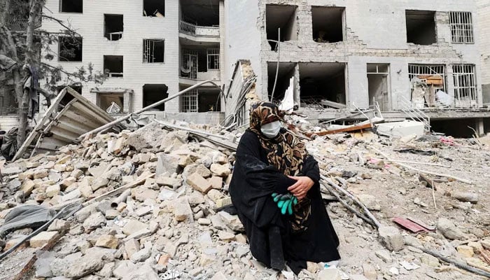 A woman sits outside her destroyed apartment after it was damaged by an airstrike while she was inside, amid the US-Israeli war on Iran, in Tehran, Iran, March 12, 2026. — Reuters