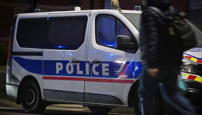 A pedestrian walks past a police vehicle parked along a street in Le Havre. — AFP/File