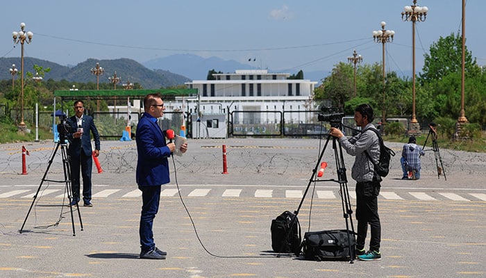 Members of the media report with the President house building in the background, as Pakistan prepares to host the U.S. and Iran for peace talks, in Islamabad, Pakistan, April 10, 2026. — Reuters