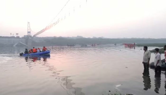 People look on as rescuers in boats work at the site of a suspension bridge collapse in Morbi town in the western state of Gujarat, India, October 31, 2022. — Reuters