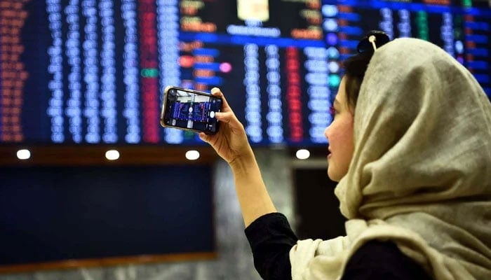A girl is seen taking picture of electronic screen with her mobile phone at the Pakistan Stock Exchange in Karachi on Wednesday, December 21, 2022. —PPI