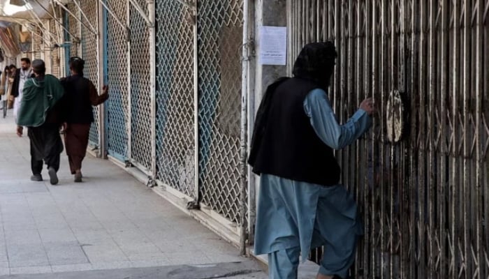 Afghan men walk past shops closed in solidarity with victims of an attack by unidentified armed men on the outskirts of the Sayed Mohammad Agha Shia shrine. — AFP