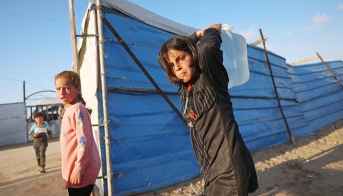 A girl carries a water container at a makeshift camp in Khan Younis in Gaza. —AFP/File