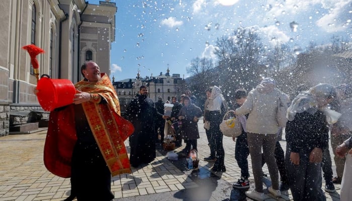 A priest sprays holy water on parishioners outside a cathedral during Orthodox Easter celebrations amid the Russia-Ukraine conflict in Donetsk, a Russian-controlled city of Ukraine, April 12, 2026.—Reuters