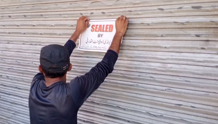 An official is pasting a SEALED notice on a sealed shop during anti-encroachment operation along High Court Road, Rawalpindi by the Rawalpindi Development Authority (RDA),  on April 13, 2026. — Facebook@RawalpindiDevelopmentAuthority/Screengrab