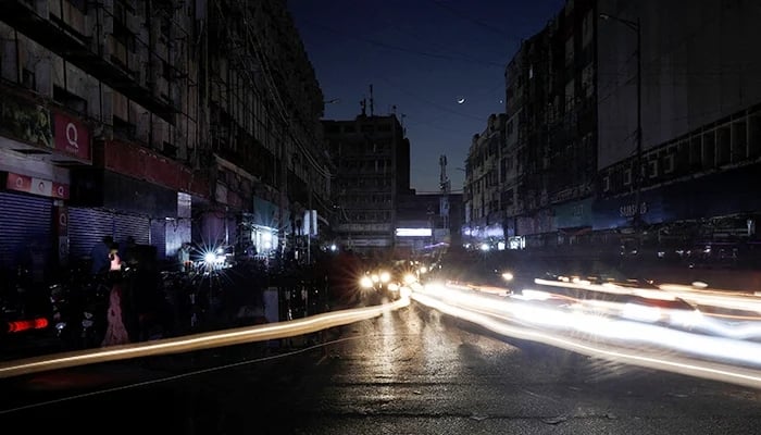 A man sits outside his shop during a country-wide power breakdown in Karachi, on January 23, 2023. — Reuters