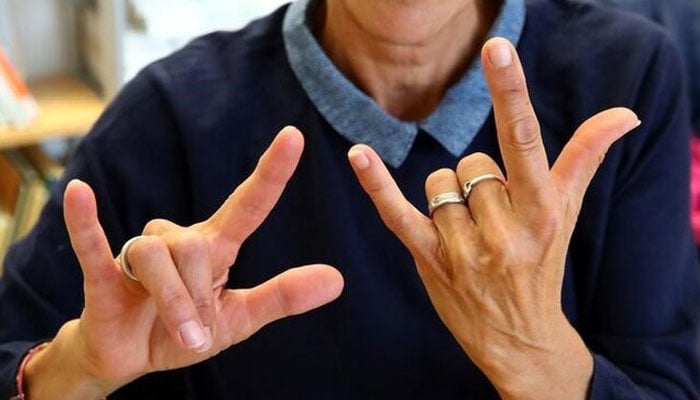 The representational image shows a teacher of sign language saying I love you with her hands. — Reuters/File