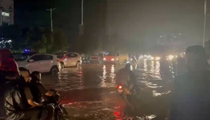 Partially submerged vehicles move after the monsoon rain in Karachi on August 19, 2025. — Geo News