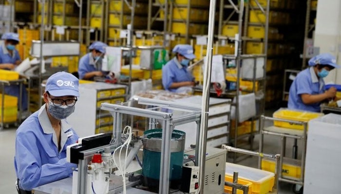 Employees wearing face masks work at a factory of the component maker SMC in Beijing, China. — Reuters/File