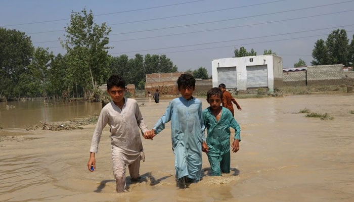 Three boys crossing floodwater in Charsadda, Khyber Pakhtunkhwa, Pakistan. — SRSP/File