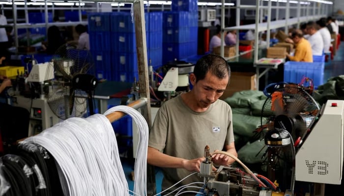 An employee works on USB cables production at a plastic accessories factory, as rising oil prices drive up production costs for plastic manufacturers, in Dongguan, Guangdong province, China, April 2, 2026.—Reuters