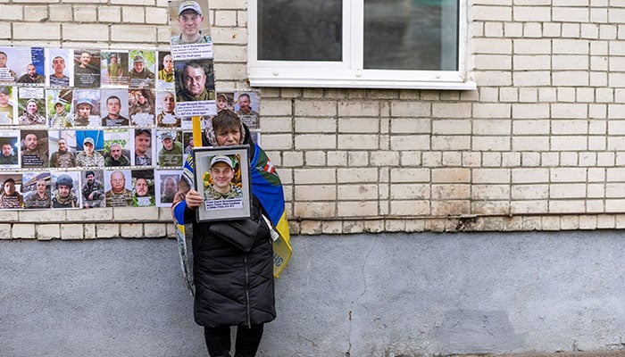 A woman holds pictures of missing Ukrainian soldiers as some of their comrades return from captivity after a prisoner of war (POW) swap, amid Russias attack on Ukraine, in an undisclosed location in Ukraine, April 11, 2026. — Reuters