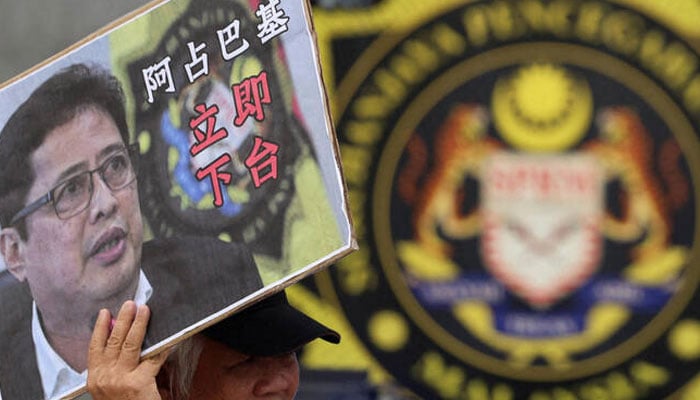 A person holding a placard with the photo of Azam Baki. —AFP/File