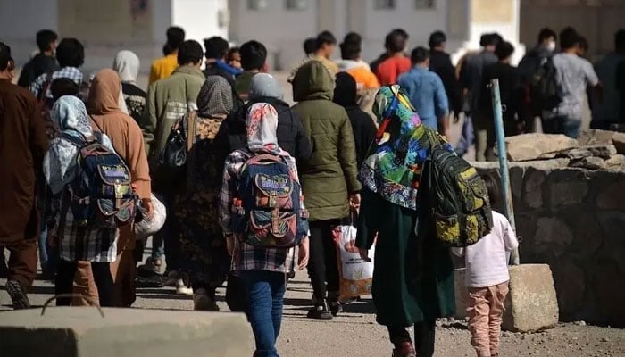 In this picture taken on October 19, 2021, Afghans who were deported back from Iran to Afghanistan walk towards the border between Afghanistan and Iran at Islam Qala port. — AFP