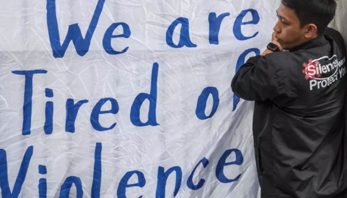 A person installs a banner bearing an anti-violence slogan in Indonesia. — Reuters/File