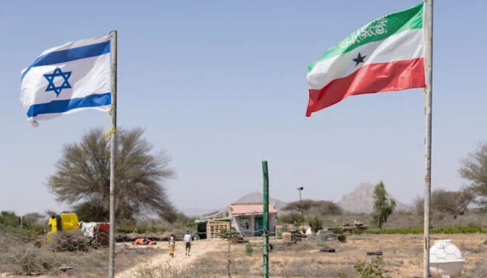 People walk by the flags of Israel and Somaliland flying alongside each other at the entrance to a fruit farm between the Somaliland capital city of Hargeisa and port city of Berbera on February 19, 2026. — AFP