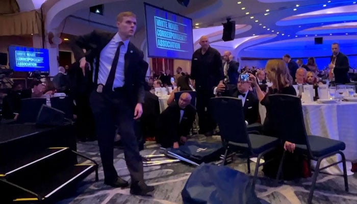 A Secret Service agent unholsters his gun, shortly after US President Donald Trump was evacuated, after a man opened fire with a shotgun on security personnel outside the room during the annual White House Correspondents Association dinner in Washington, DC. ─ Reuters