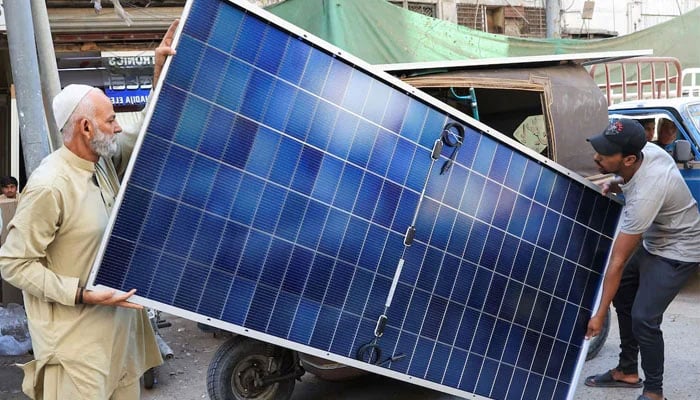 Men load solar panels on a rickshaw at a market, in Karachi, on March 26, 2025. — Reuters