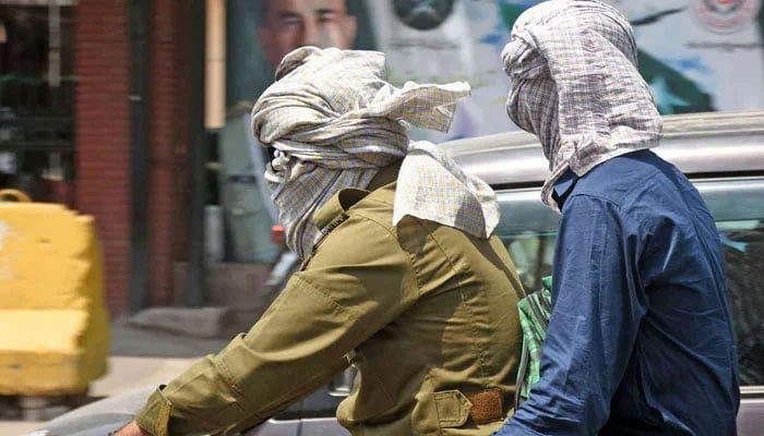 Bikers cover their faces with clothes to protect from hot winds during high temperature in Lahore on May 15, 2025. — Online