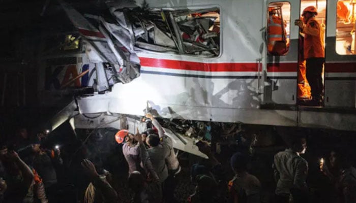 Rescue workers working on one of the trains. —AFP