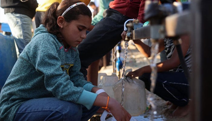 A Gaza kid filling a water bottle from a tap. —AFP/File