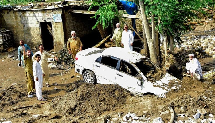 People struggle to retrieve a car from mud and debris after flash floods in the Buner district of monsoon-hit KP on August 16, 2025. — AFP