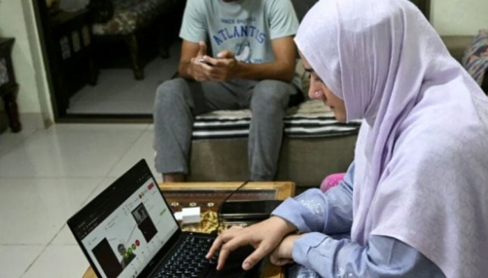 Dr Saniya Jafri conducts an online consultation, alongside her daughter in Karachi, in this undated image. — AFP