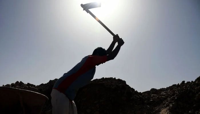 The representational image shows a labourer using an axe at a work site in Karachi. — Online/File