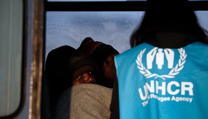 A Congolese refugee looks on as a UNHCR volunteer checks on refugees and migrants rescued at open sea and waiting to be transferred to the Moria registration centre at the port of Mytilene on the Lesbos island, Greece March 21, 2016. — Reuters