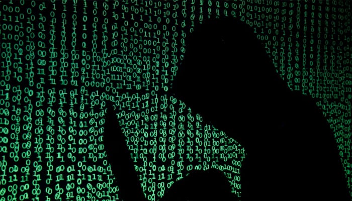 A hooded man holds a laptop computer as cyber code is projected on him in this illustration picture taken on May 13, 2017. — Reuters