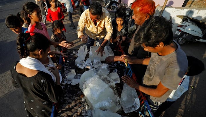 A man breaks a block of ice to distribute it among the residents of a slum during hot weather in Ahmedabad, India, April 28, 2022. — Reuters