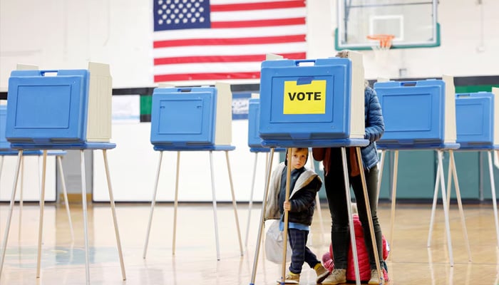A boy peers out from under a voting booth as his mother marks her ballot during the state’s primary election to choose candidates for the November midterm elections, in Cary, North Carolina, US, March 3, 2026. — Reuters