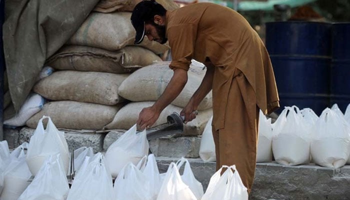 The representational image shows a Pakistani worker preparing bags of wheat flour. — AFP/File