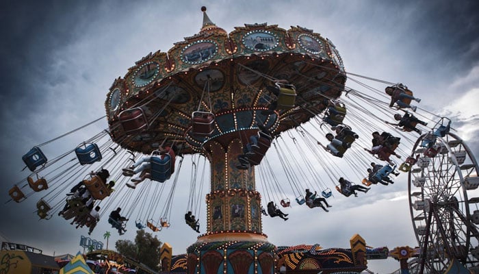 The representational image shows people enjoying a thrilling swing carousel at a lively amusement park. — Pexels/File