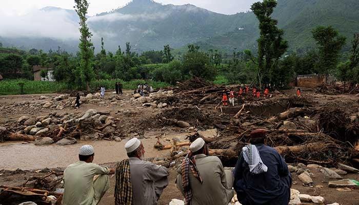 Residents sit as rescuers search for bodies amid debris of damaged houses following a storm that caused heavy rains and flooding, in KPs Bayshonai Kalay in Buner district on August 17, 2025. — Reuters