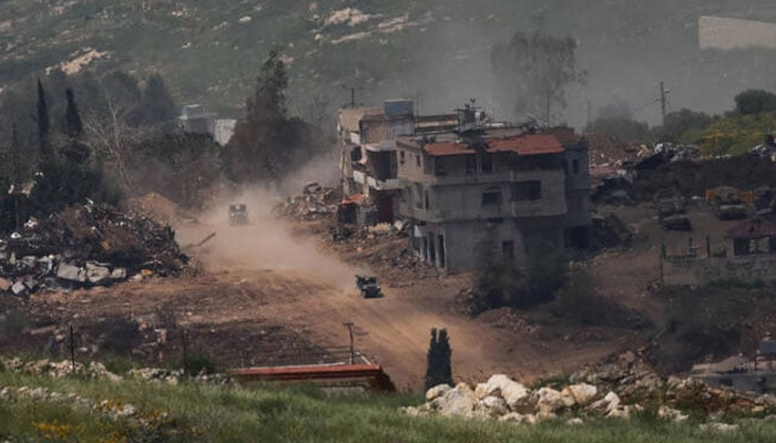 Israeli military vehicles move next to damaged buildings in southern Lebanon, near the Israel-Lebanon border, as seen from northern Israel, Apr. 27, 2026. —Reuters