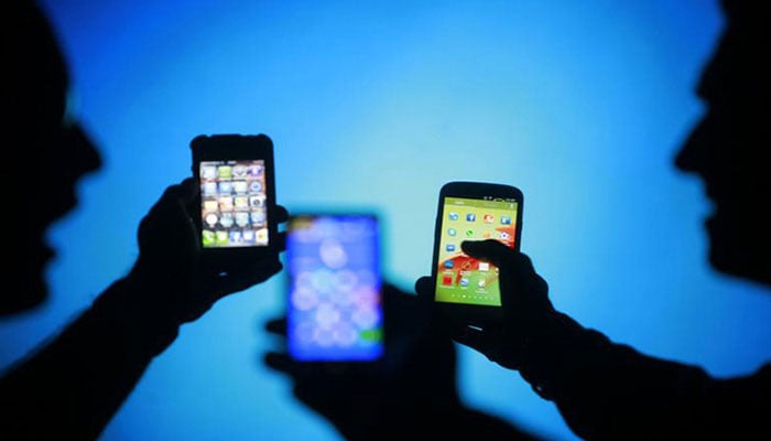 This representational image shows three people looking at their mobile screens. — Reuters/File