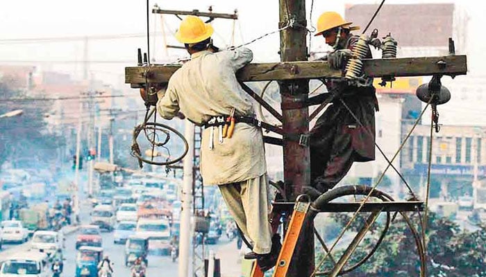 The representational image shows two linemen in Pakistan engaged in essential power infrastructure maintenance. — The News/File