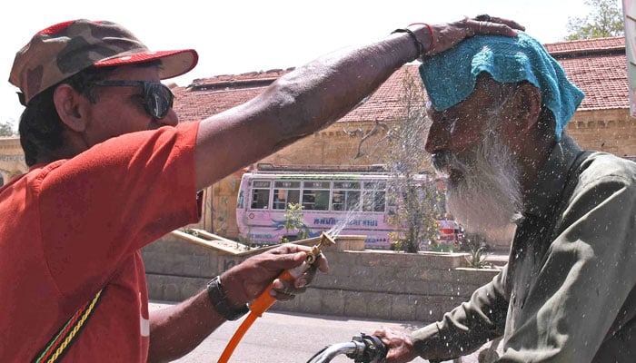 A volunteer of the Edhi Foundation sprays water on a passerbys head to cool off on a hot summer day in Karachi, on May 4, 2026. — ONLINE