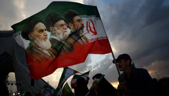A man holds a flag with a picture of late leader of the Islamic Revolution Ayatollah Ruhollah Khomeini, late Supreme Leader of Iran Ayatollah Ali Khamenei and Irans new Supreme Leader Mojtaba Khamenei, during a rally in Tehran, Iran, April 29, 2026.—Reuters