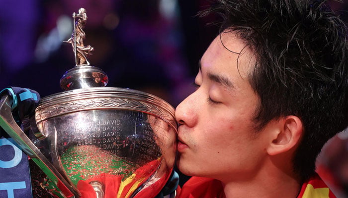 Chinas Wu Yize kisses the trophy after his win at the World Snooker Championship. —AFP
