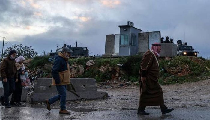 Israeli security forces keep watch as Palestinian Muslims cross the Qalandia checkpoint in the occupied West Bank city of Ramallah early on February 27, 2026, on their way to the al-Aqsa Mosque in Jerusalem for the second Friday noon prayers of Islams holy month of Ramadan.—AFP