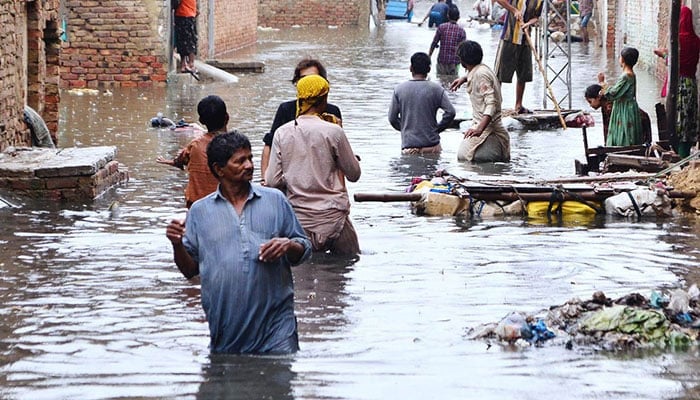 People are seen passing from accumulated rainwater after torrential rains hit Hyderabad, on August 2022. — APP