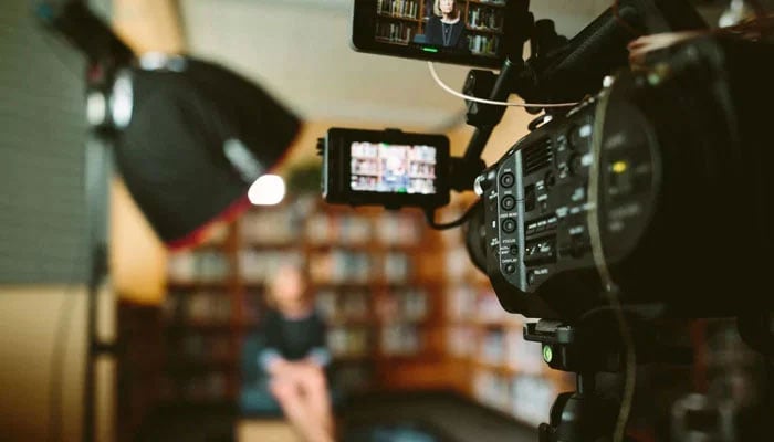 This image shows a video production setup featuring a professional camcorder. — Unsplash/File